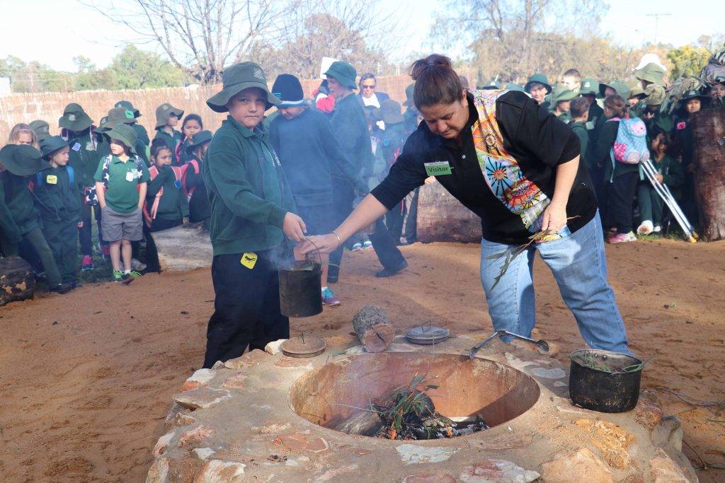 Janine Mann demonstrated to students at Cobar Public School last week what’s involved in a traditional smoking ceremony as part of the school’s Dreaming Day activities.  Pictured also participating in the ceremony is student Zac Boland. 